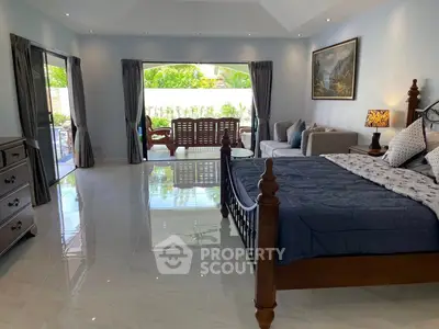 Spacious bedroom with elegant decor and garden view, featuring a cozy seating area and luxurious bedding.