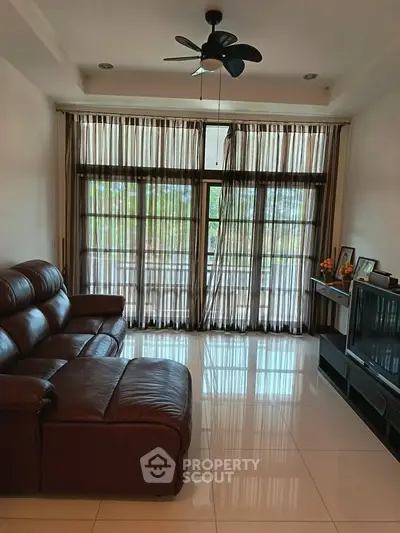 Spacious living room with leather sofa and large windows offering natural light and scenic views.