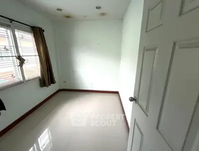 Spacious empty room with large window and white walls, perfect for customization.