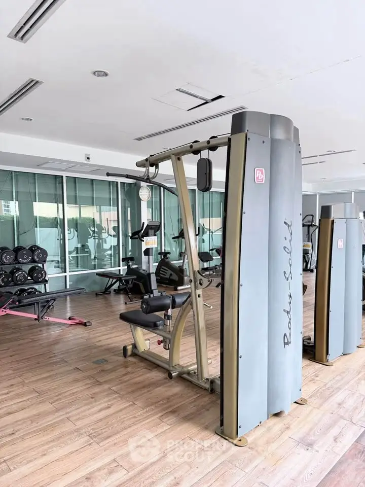 Spacious modern gym with state-of-the-art fitness equipment and wooden flooring.