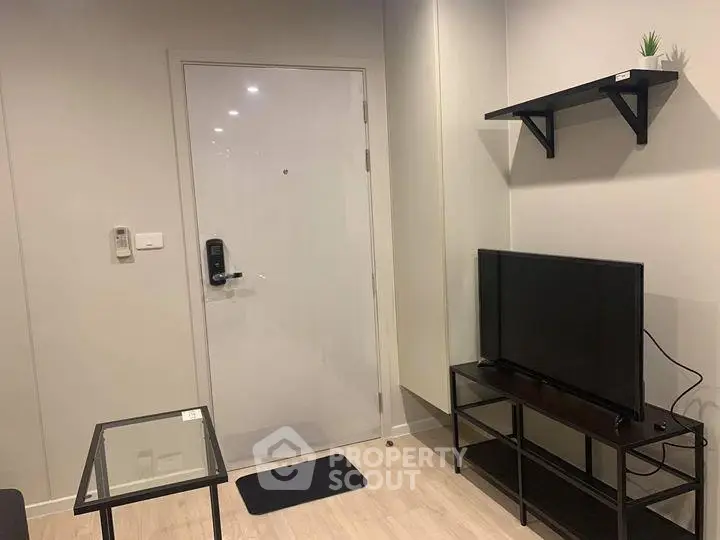 Modern living room with sleek TV stand and glass coffee table, featuring a secure digital door lock.