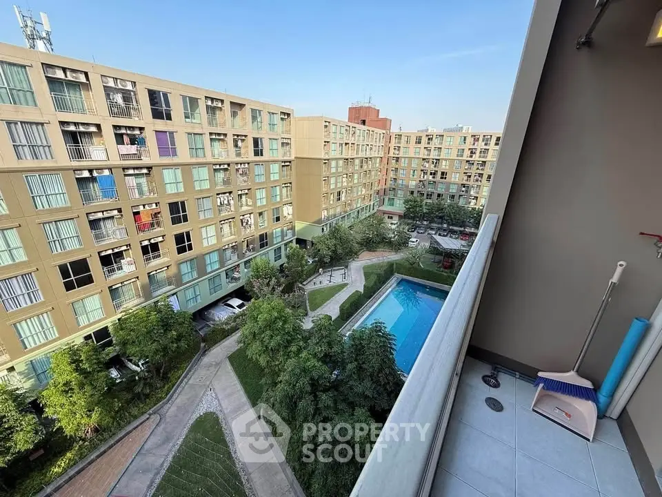 Spacious apartment balcony with stunning pool and garden view in modern residential complex.