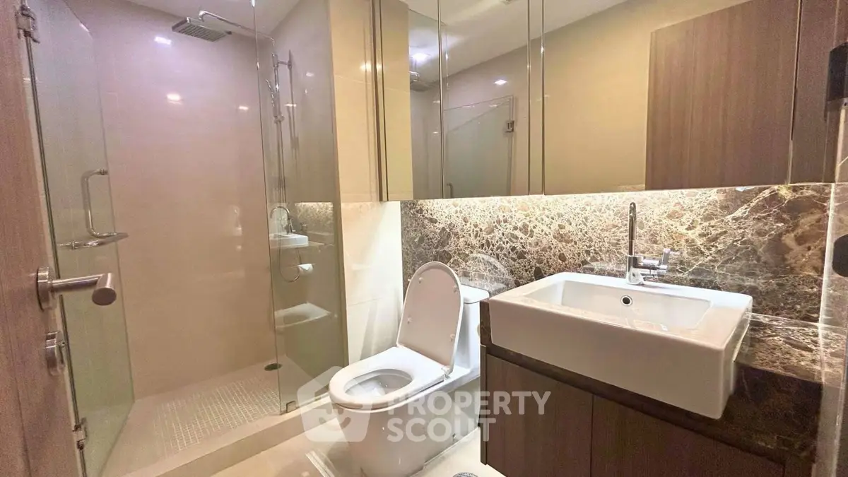 Modern bathroom with glass shower and stylish sink in luxury apartment