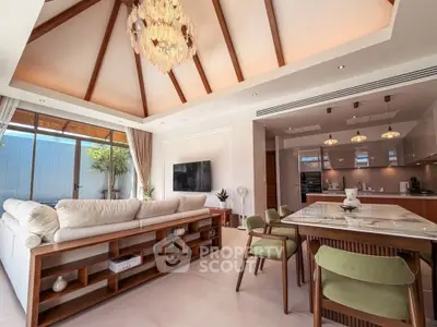 Luxurious open-plan living room with high ceilings and elegant chandelier, featuring modern kitchen and stylish decor.