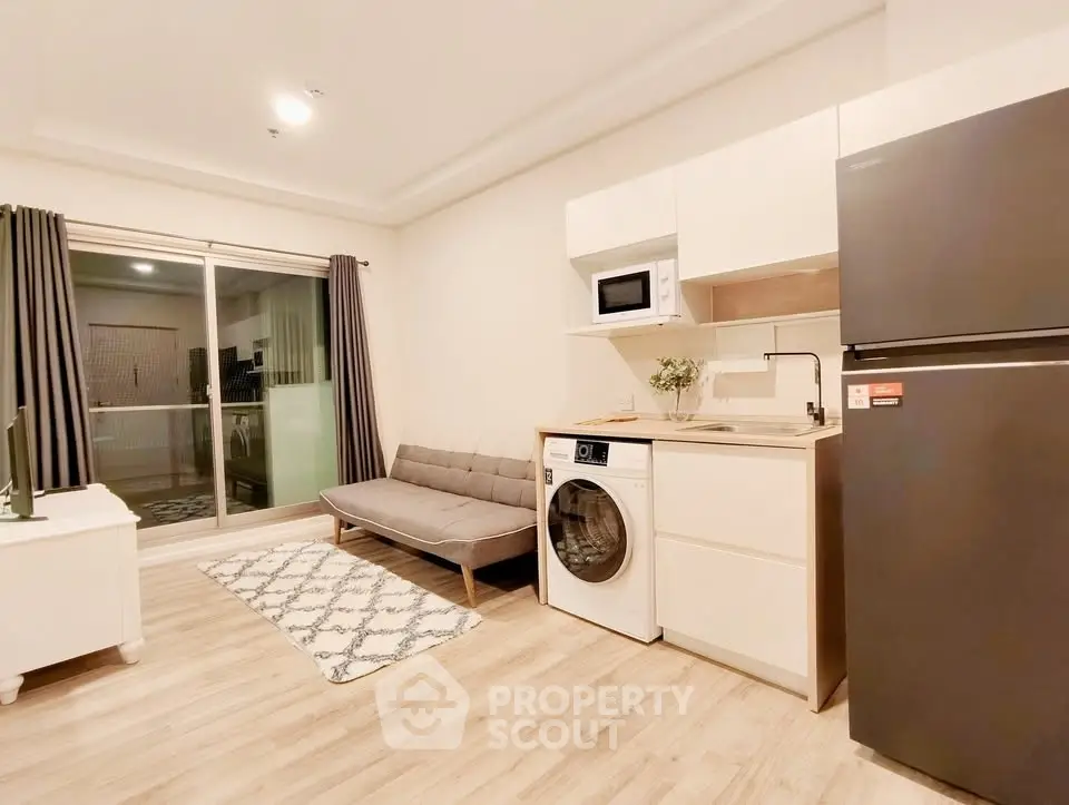 Modern studio apartment with open kitchen, washing machine, and cozy living area.