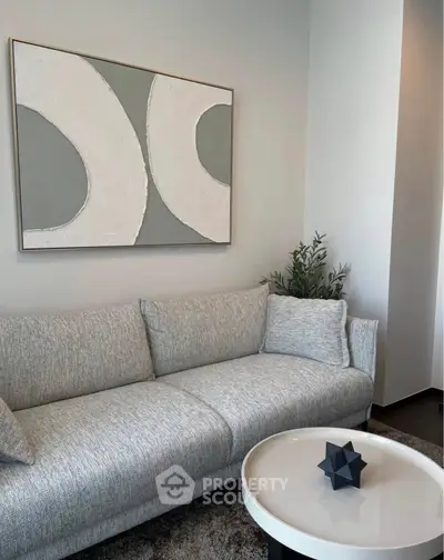 Modern living room with stylish gray sofa and abstract wall art