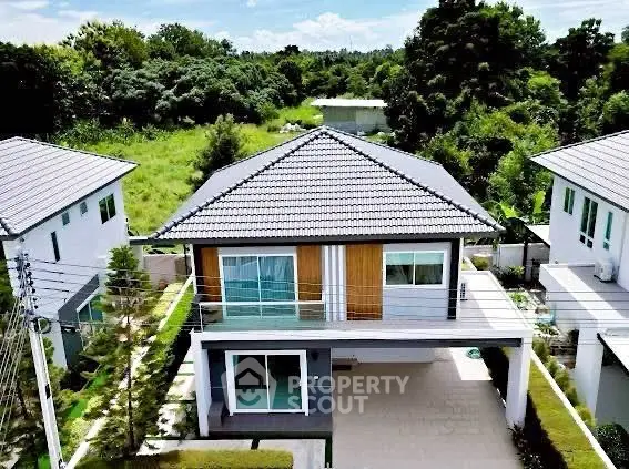 Charming two-story house with modern design and lush greenery surroundings.