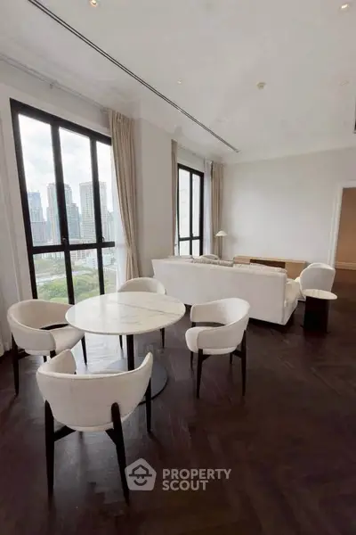 Luxurious living room with city view, elegant furniture, and dark wood flooring in high-rise apartment.