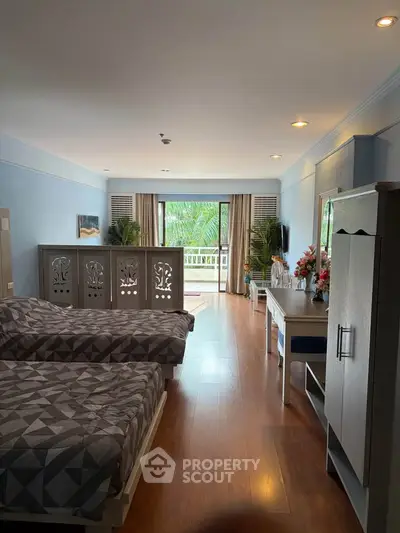 Spacious bedroom with twin beds and balcony view, featuring elegant decor and ample natural light.