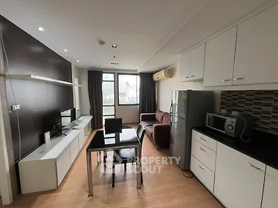 Modern living room with sleek kitchen, dining area, and city view window.