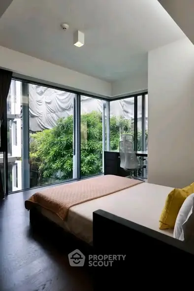 Modern bedroom with large windows and lush garden view, featuring sleek design and natural light.