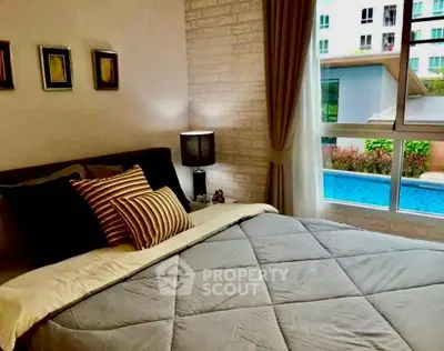 Cozy bedroom with pool view in modern apartment, featuring stylish decor and ample natural light.