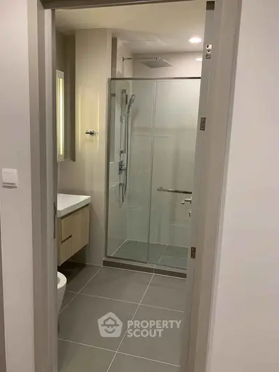 Modern bathroom with glass shower and sleek fixtures in contemporary apartment.