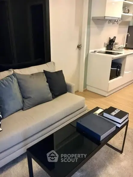 Modern living room with sleek kitchen, stylish sofa, and chic decor in a cozy apartment.