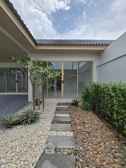 Modern house exterior with landscaped garden and stone pathway under a clear sky.