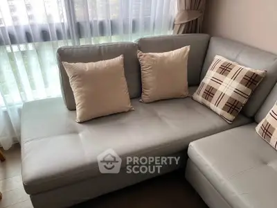 Cozy living room with stylish gray sectional sofa and decorative pillows by a sunlit window.