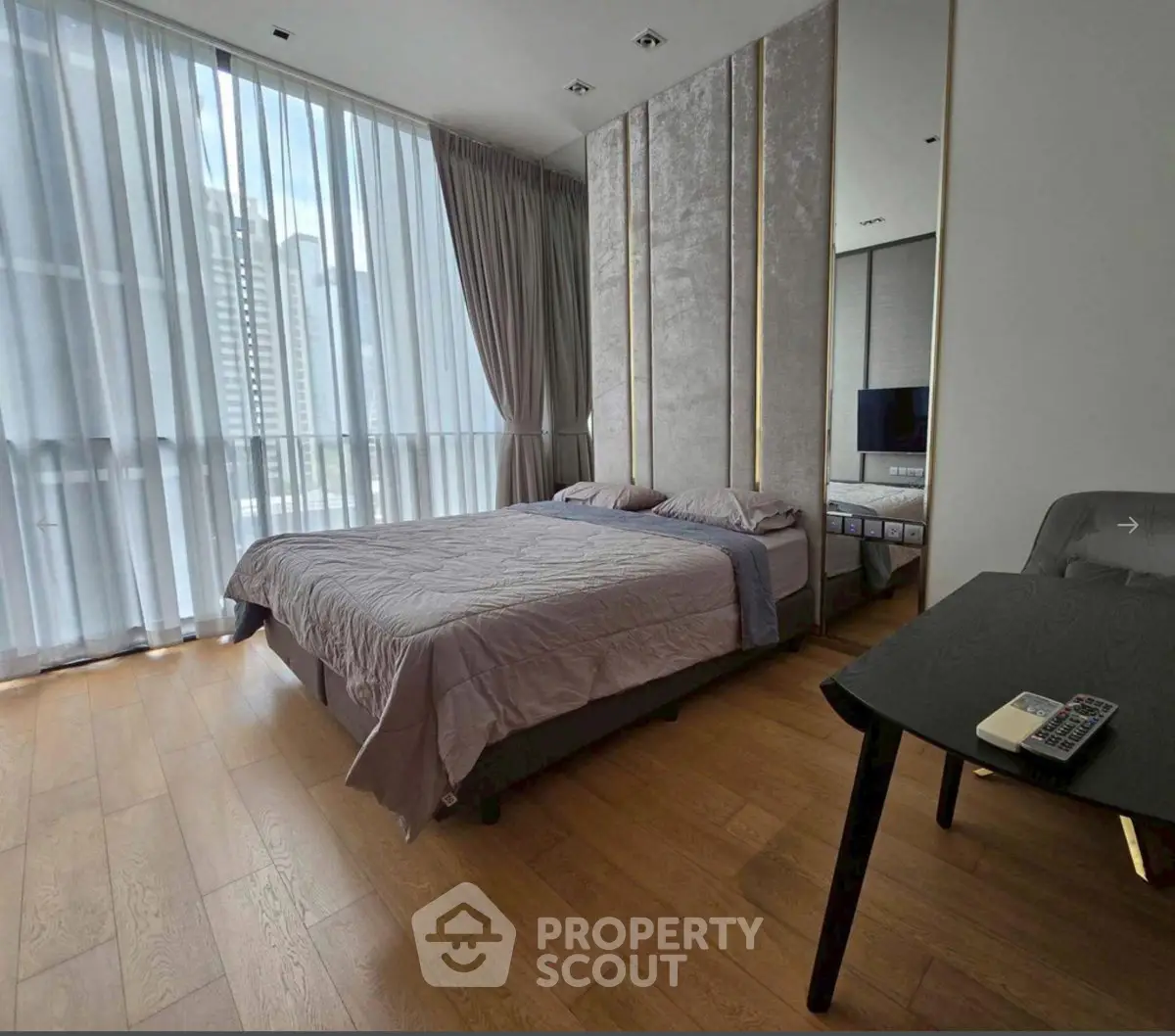Luxurious bedroom with floor-to-ceiling windows and modern decor in a high-rise apartment.