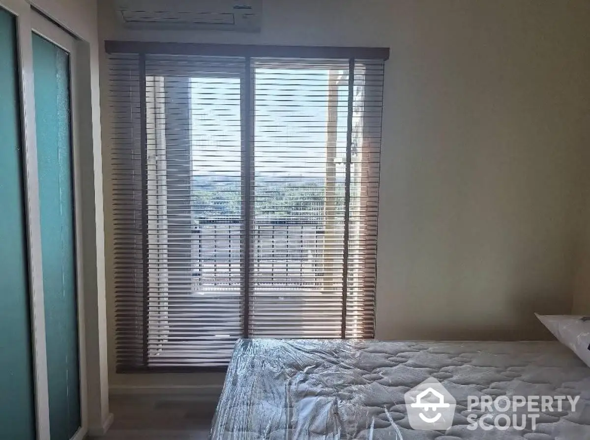 Bright bedroom with balcony view and modern blinds, perfect for relaxation.