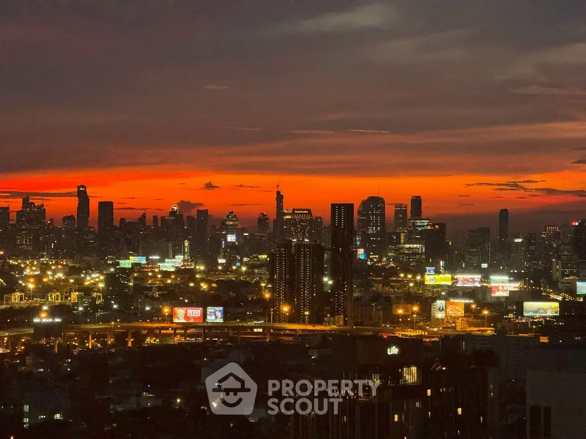 Stunning city skyline view at sunset with vibrant orange sky and illuminated buildings.