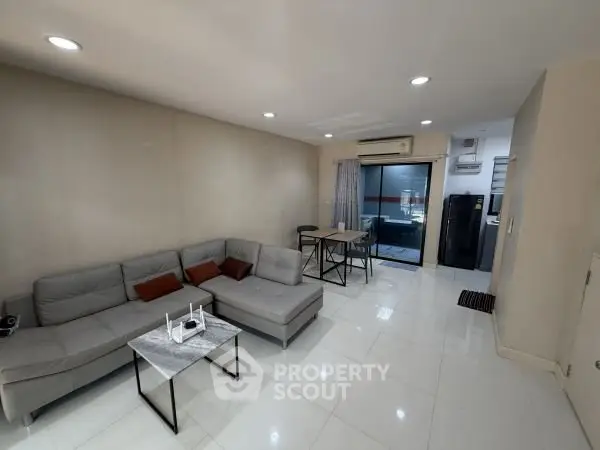 Modern living room with sleek furniture and open layout, featuring a cozy sofa and dining area.