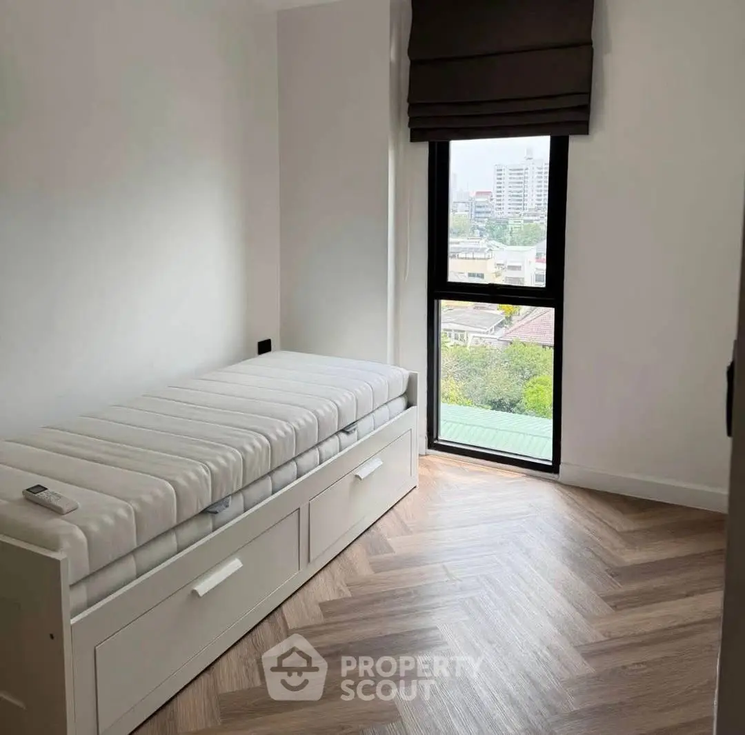 Minimalist bedroom with single bed and city view window, perfect for urban living.