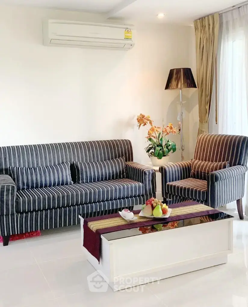 Elegant living room with striped sofa, armchair, and modern decor in a bright, airy space.