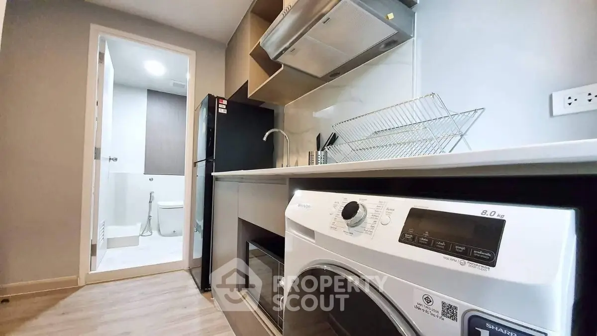 Modern kitchen with washing machine and view into bathroom