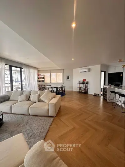 Spacious modern living room with open kitchen and city view, featuring elegant parquet flooring.