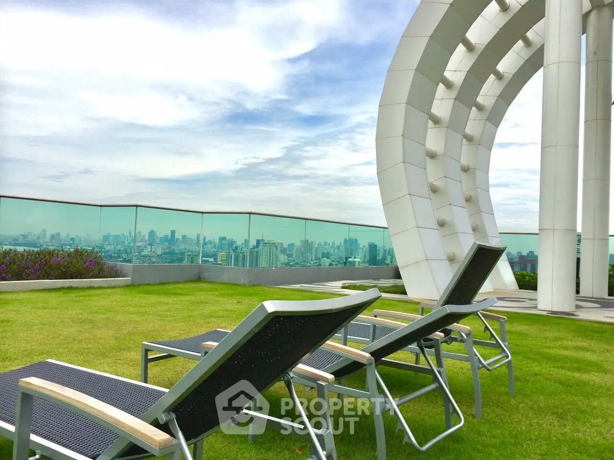 Luxurious rooftop with stunning city view and modern lounge chairs on green lawn.