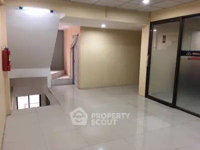 Spacious commercial interior with tiled flooring and glass partition, ideal for office or retail setup.