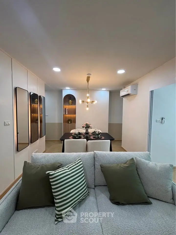 Modern living room with stylish decor and dining area, featuring elegant lighting and cozy seating.