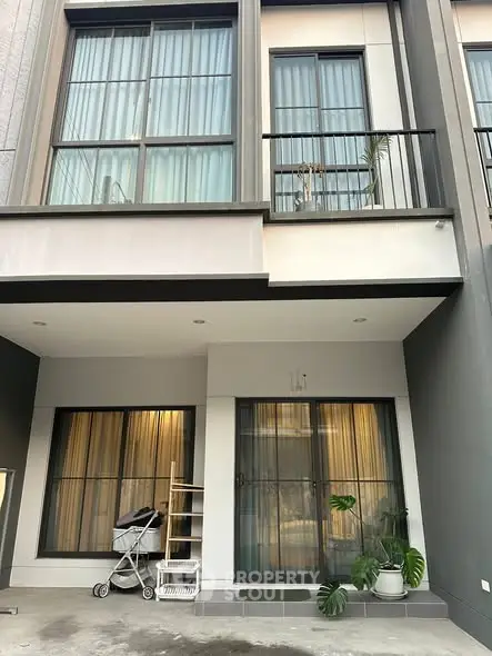 Modern townhouse exterior with large windows and balcony, featuring a sleek design and contemporary architecture.