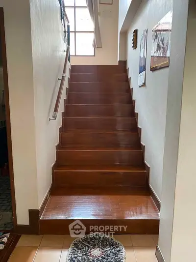 Elegant wooden staircase with natural light and decorative accents in a cozy home setting.