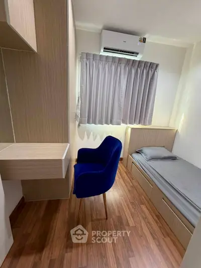 Cozy bedroom with wooden flooring, built-in storage, and air conditioning, perfect for a compact living space.