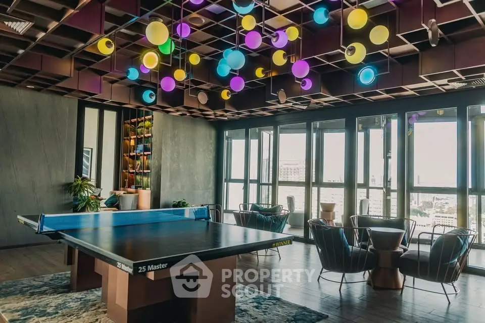 Stylish game room with ping pong table and vibrant ceiling lights in modern building.