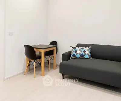Modern minimalist living room with sleek black sofa and compact dining set.