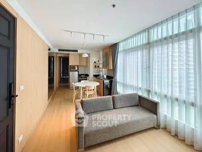 Modern living room with open kitchen and large windows in a high-rise apartment.