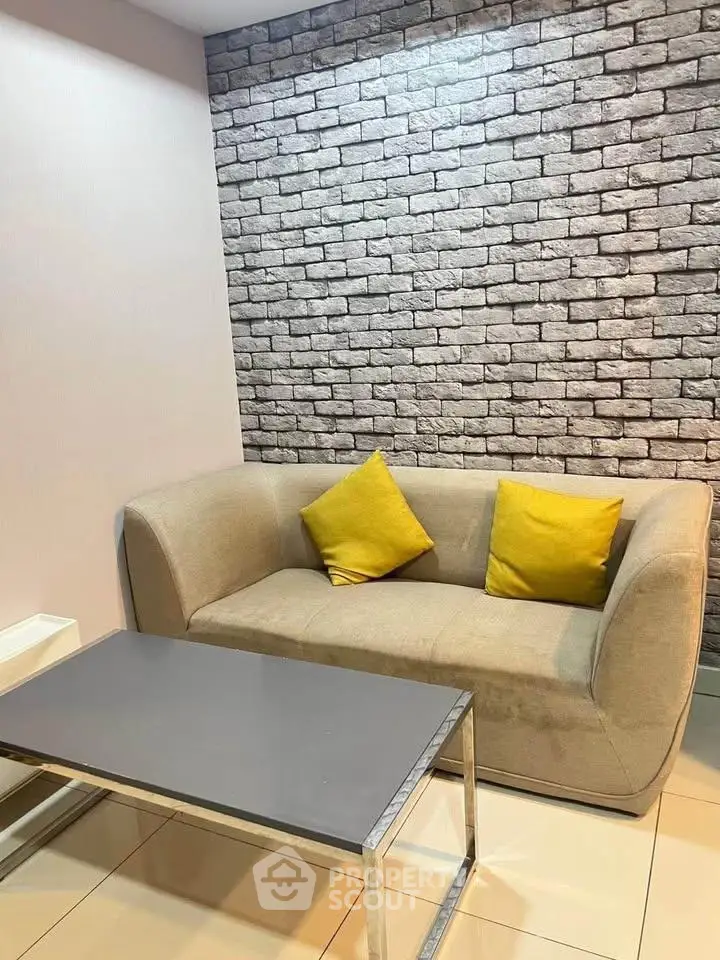 Modern living room with stylish brick wall and cozy beige sofa with yellow cushions.