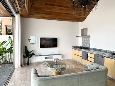 Luxurious open-plan living room with modern kitchen and elegant decor, featuring a stylish chandelier and lush greenery.