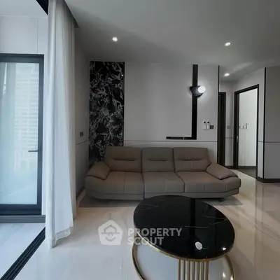 Modern living room with sleek sofa and marble coffee table, featuring large windows and elegant decor.