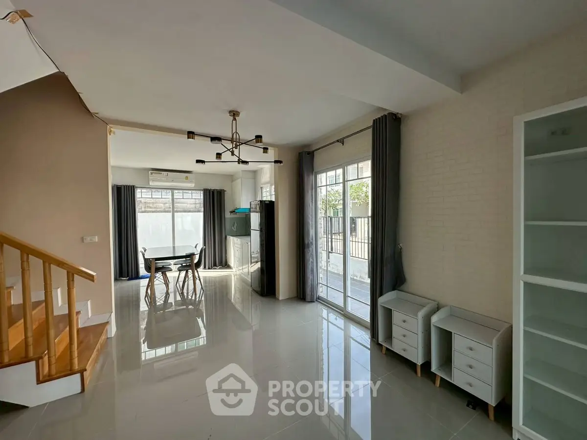 Spacious modern living room with large windows and elegant staircase