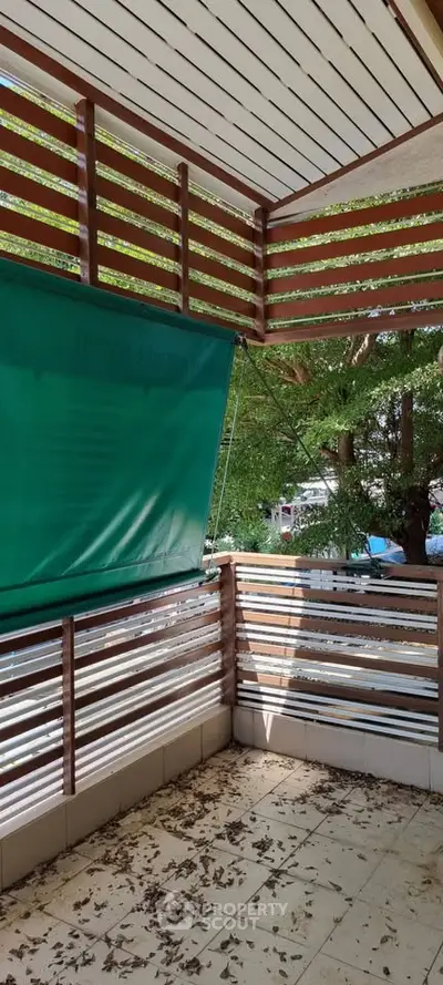 Charming balcony with wooden slats and green awning, perfect for relaxation.