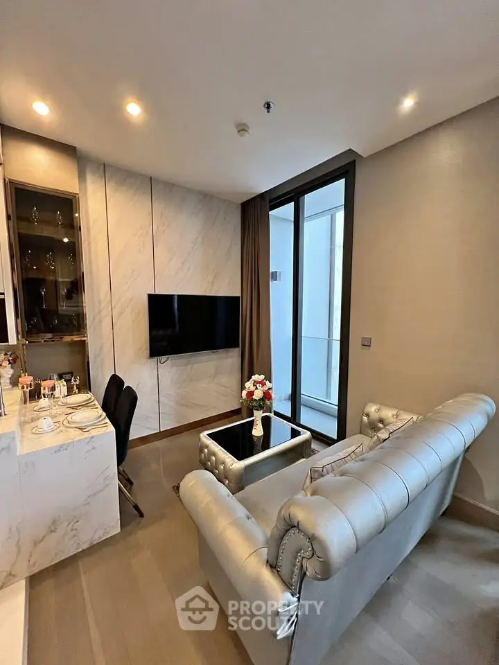 Modern living room with elegant sofa and TV, featuring a sleek open layout and balcony access.