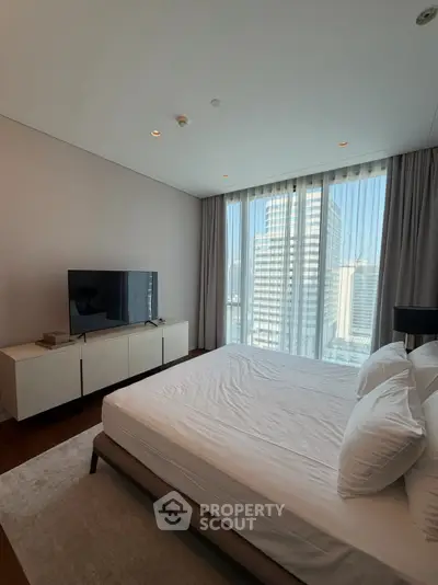 Luxurious bedroom with city view, featuring modern furniture and large windows for natural light.