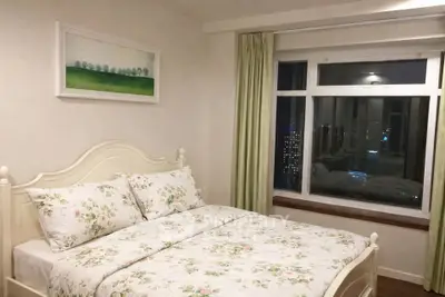 Cozy bedroom with floral bedding and city view from large window