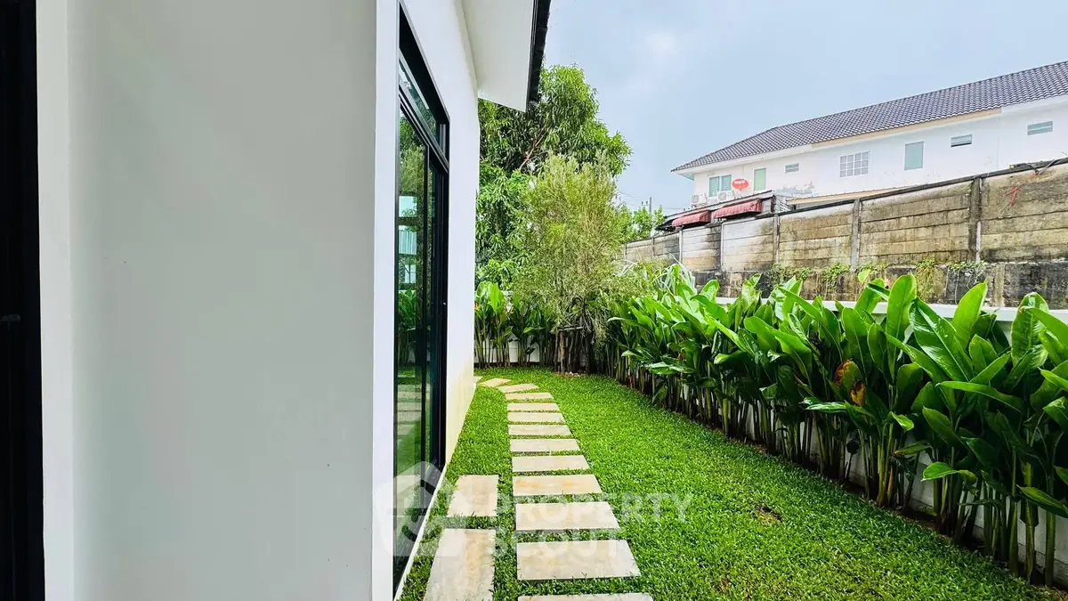 Charming garden view with lush greenery and stepping stone path beside modern home exterior.