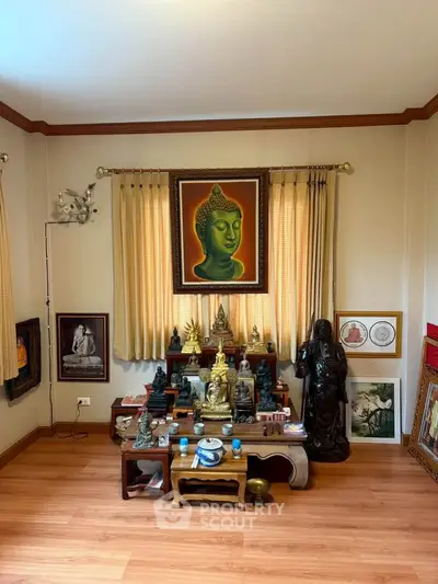 Serene living room with Buddha art and wooden flooring, perfect for meditation and relaxation.