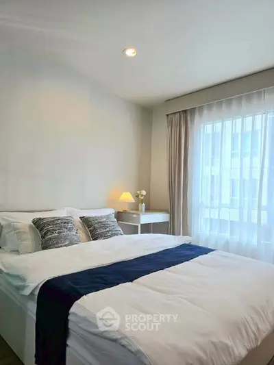 Cozy and bright bedroom with modern decor and large window for natural light.