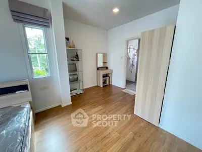 Spacious bedroom with wooden flooring and natural light, featuring a vanity and open closet.