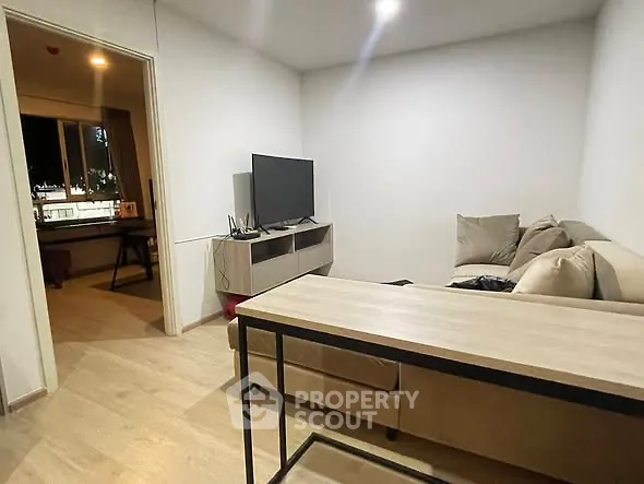 Modern living room with cozy sectional sofa and flat-screen TV, open doorway to adjacent room.